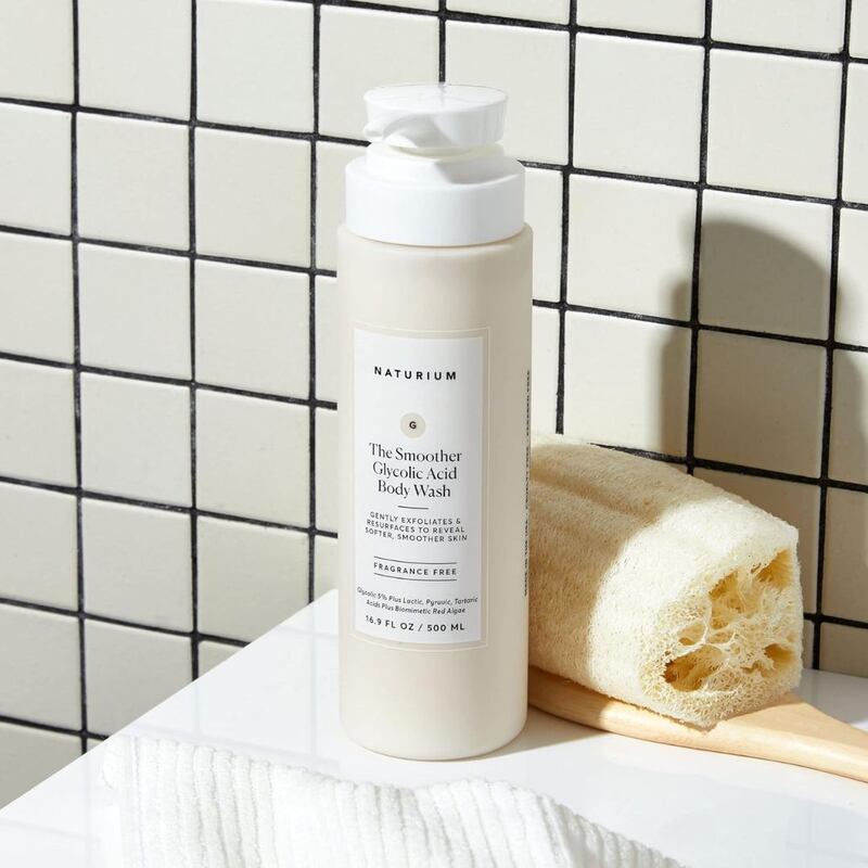 A bottle of Naturium body wash next to a loofah.